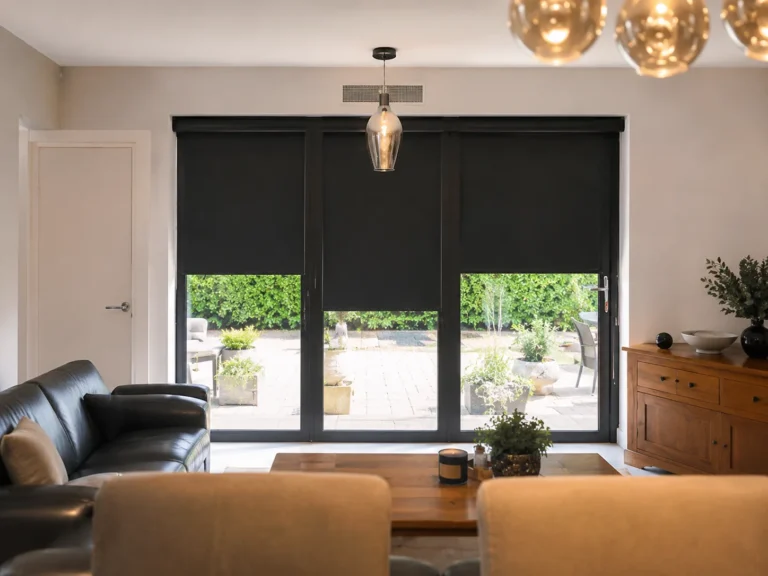 Dark roller blinds fitted across large patio doors, creating a blackout-style effect.