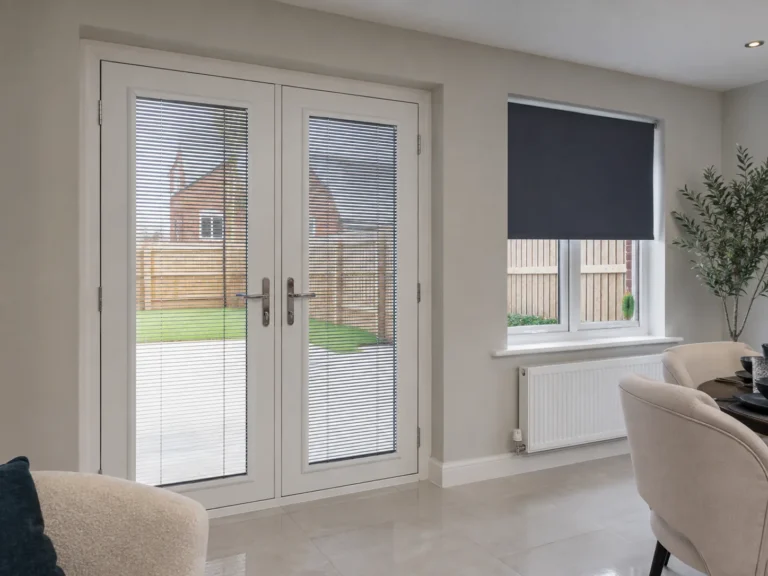 Slim fitted door blinds on white French doors beside a dark roller blind on a window.