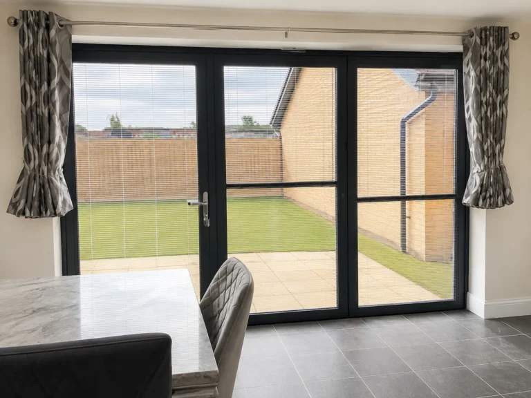Slim fitted Venetian-style blinds installed on black-framed glazed doors.